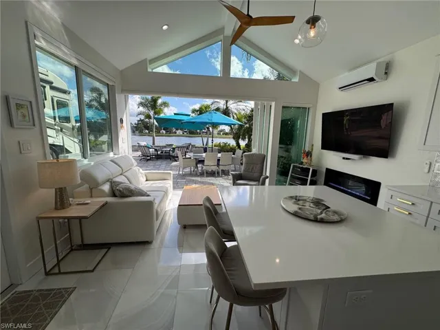 Tiled living room with high vaulted ceiling, a wealth of natural light, and a wall mounted air conditioner