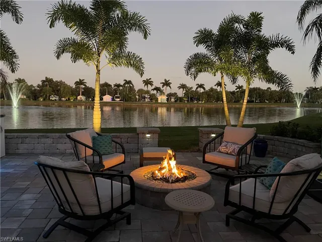 Patio terrace at dusk featuring a water view and a fire pit