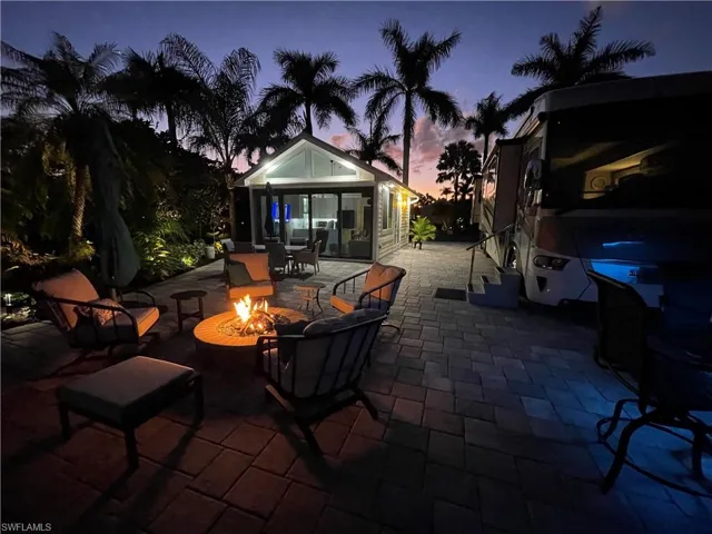 Patio terrace at dusk with a sunroom and an outdoor fire pit