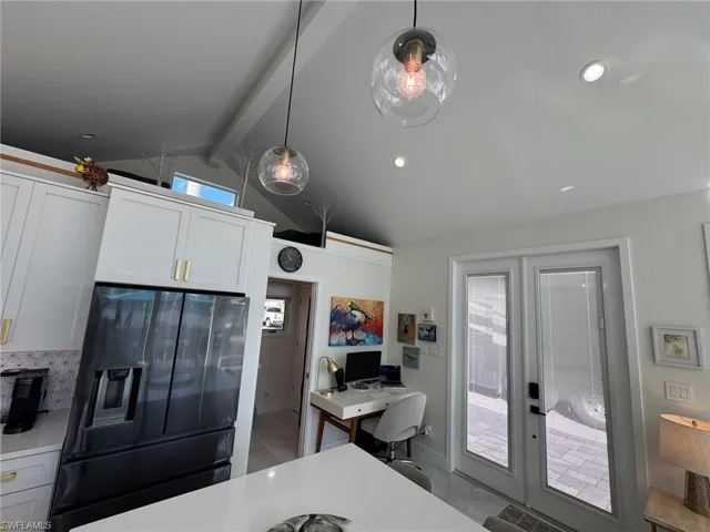 Kitchen with white cabinetry, decorative light fixtures, vaulted ceiling with beams, french doors, and fridge with ice dispenser