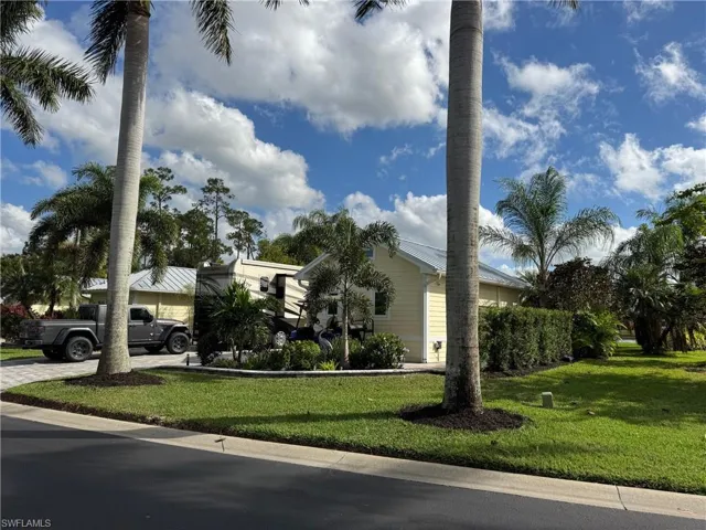 View of property hidden behind natural elements with a front lawn
