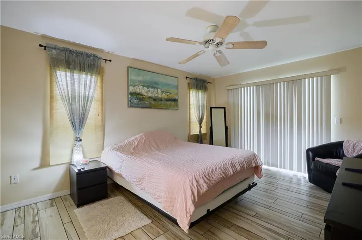 Bedroom with light wood-type flooring, multiple windows, and ceiling fan