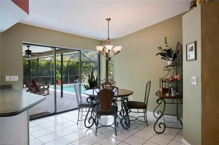Dining room with light tile patterned floors, a sunroom, a chandelier, and ceiling fan
