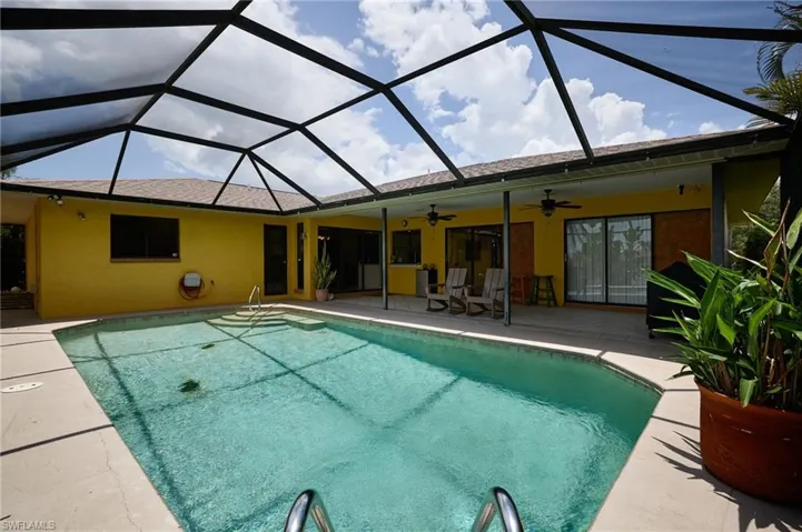 Swimming pool with a ceiling fan, a patio, and glass enclosure