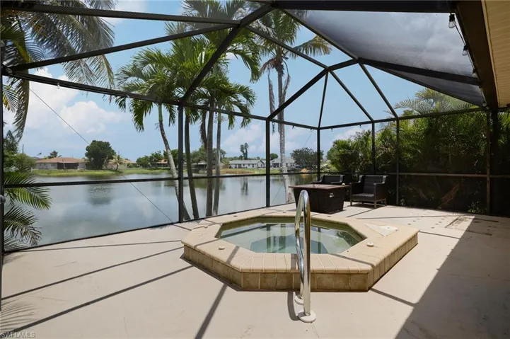 View of pool with an in-ground hot tub, a patio, a water view, and glass enclosure