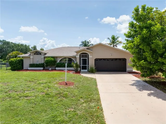 Single story home with a garage, stucco siding, a front yard, and driveway