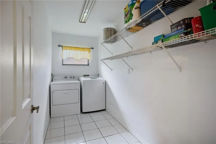 Laundry room with separate washer and dryer and light tile patterned floors