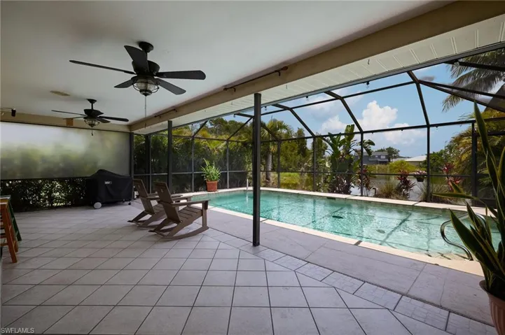 Outdoor pool with a patio area, a ceiling fan, grilling area, and a lanai