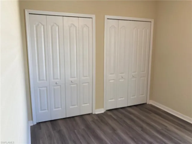 Unfurnished bedroom featuring multiple closets and dark wood-type flooring