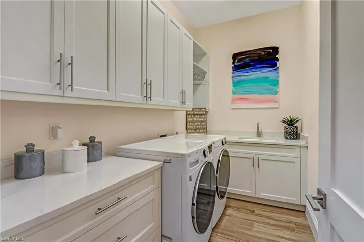 Washroom with separate washer and dryer, sink, cabinets, and light wood-type flooring
