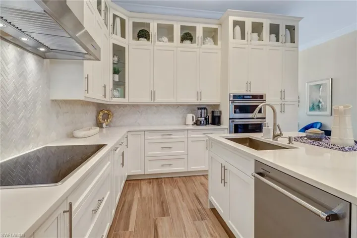 Kitchen featuring white cabinetry, sink, wall chimney range hood, and stainless steel appliances