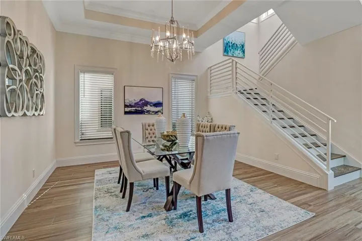 Dining space with a chandelier, light wood-type flooring, ornamental molding, and a tray ceiling