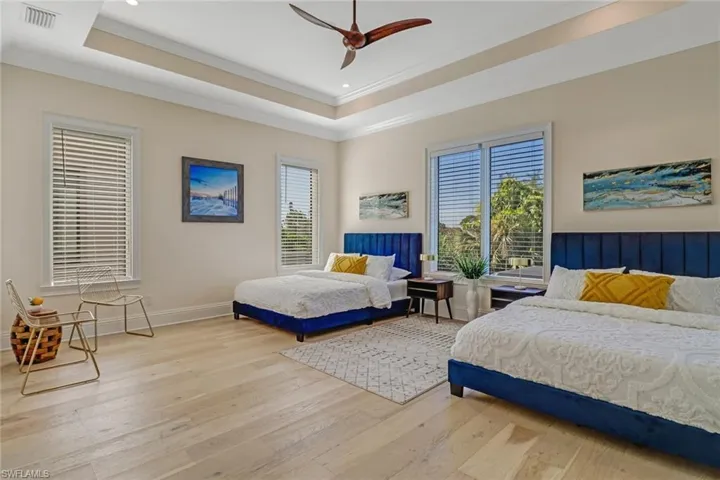 Bedroom with ceiling fan, a raised ceiling, crown molding, and light hardwood / wood-style flooring