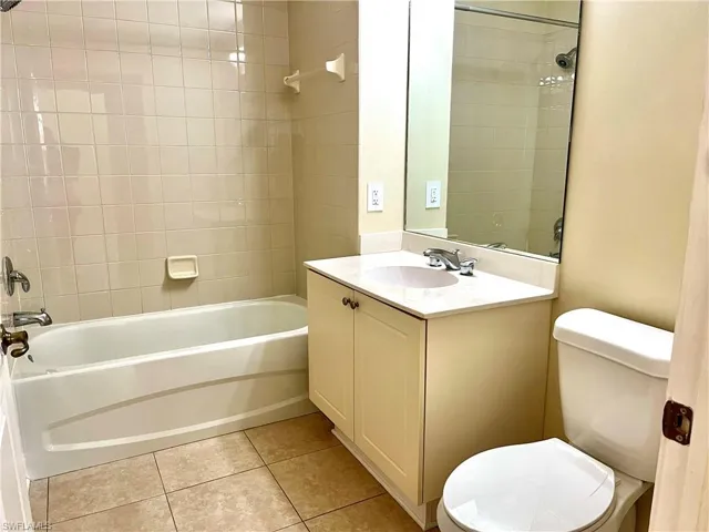 Full bathroom with tiled shower / bath combo, vanity, toilet, and tile patterned floors