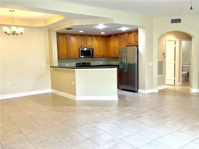 Kitchen with pendant lighting, a notable chandelier, kitchen peninsula, appliances with stainless steel finishes, and light tile patterned floors