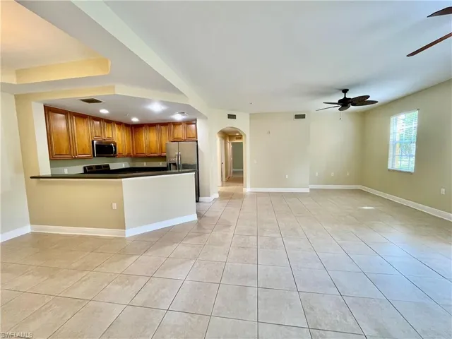Kitchen featuring ceiling fan, light tile patterned floors, appliances with stainless steel finishes, and kitchen peninsula