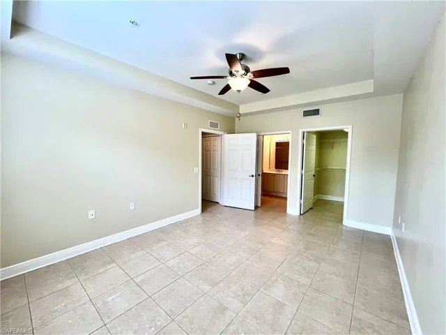 Unfurnished bedroom with light tile patterned floors, a spacious closet, ceiling fan, and a closet