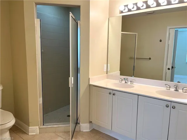 Bathroom with walk in shower, vanity, toilet, and tile patterned floors