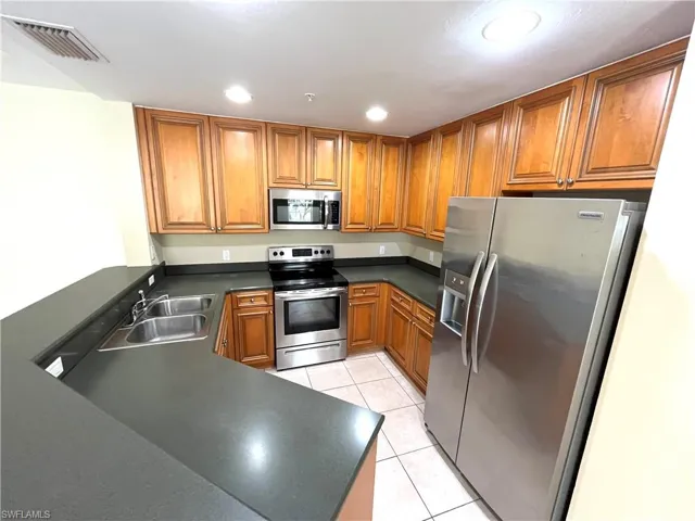 Kitchen featuring kitchen peninsula, sink, light tile patterned floors, and stainless steel appliances