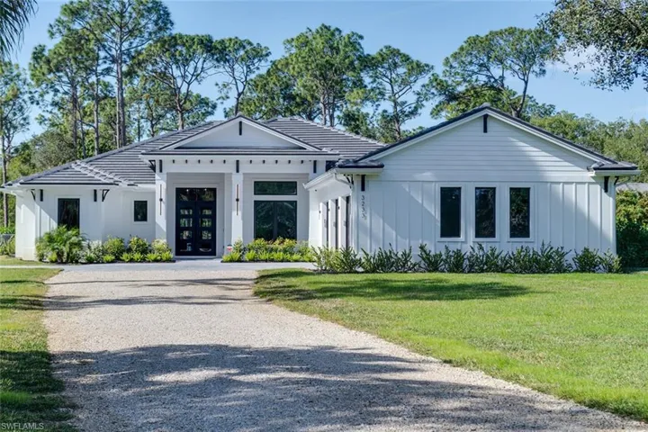 Modern inspired farmhouse with french doors, board and batten siding, driveway, and a front yard