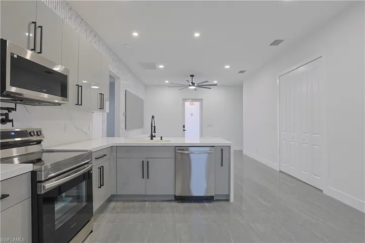 Kitchen featuring stainless steel appliances, gray cabinets, recessed lighting, ceiling fan, and modern cabinets