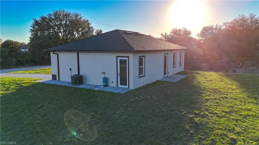 Back of house featuring a yard, stucco siding, and roof with shingles