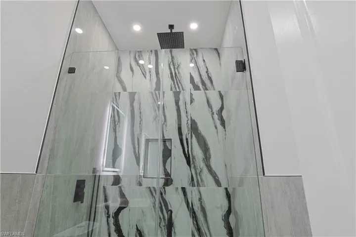 Full bath with a marble finish shower and recessed lighting