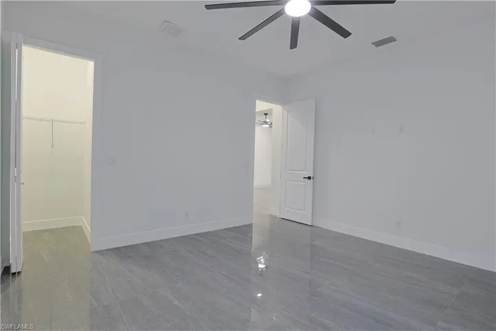 Unfurnished bedroom with a walk in closet and a ceiling fan