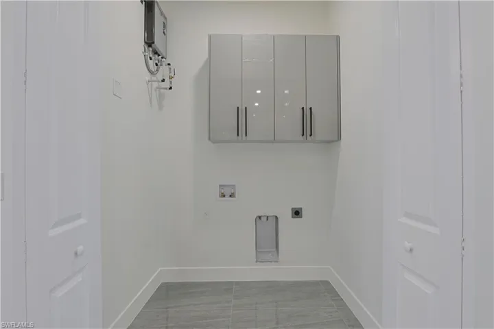 Laundry room with hookup for a washing machine, cabinet space, hookup for an electric dryer, and water heater