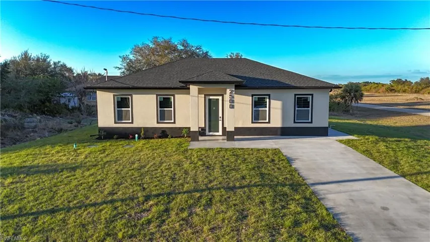 View of front of home with a front yard, stucco siding, roof with shingles, and driveway