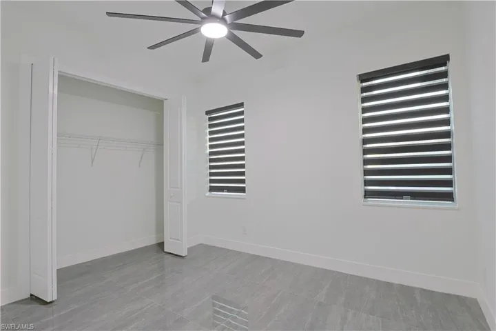 Unfurnished bedroom with a ceiling fan, a closet, and radiator