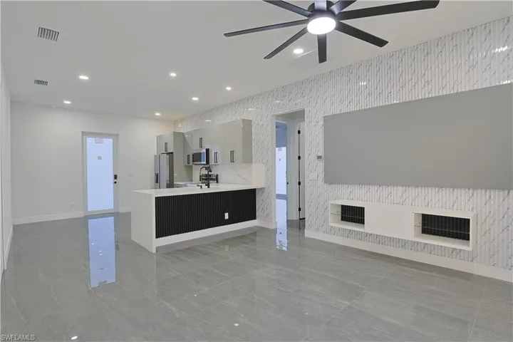 Unfurnished living room featuring wallpapered walls, recessed lighting, an accent wall, and ceiling fan