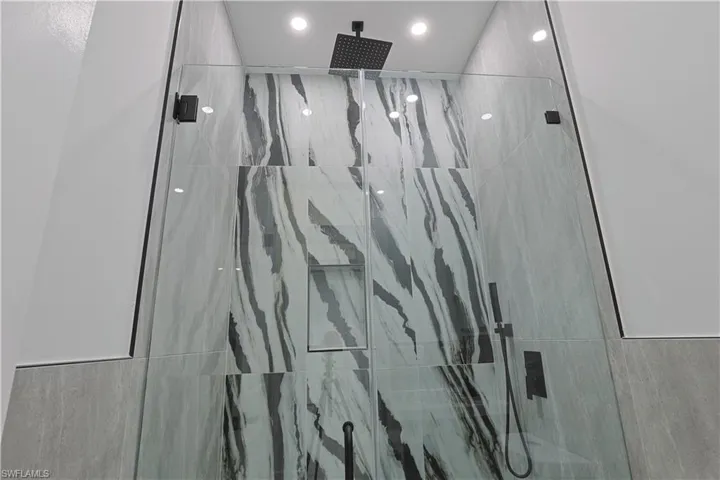 Full bathroom with a marble finish shower and recessed lighting