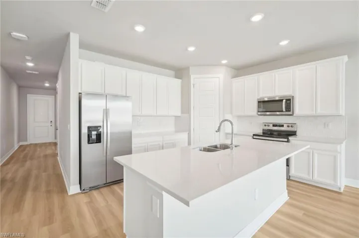 Kitchen featuring an island with sink, white cabinetry, sink, and stainless steel appliances
