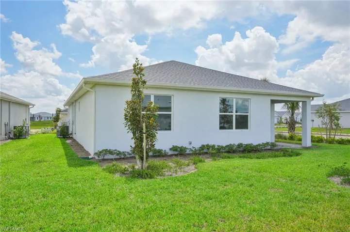 View of home's exterior with a lawn and central AC