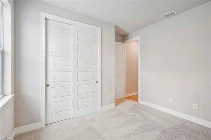 Unfurnished bedroom with light carpet and a closet