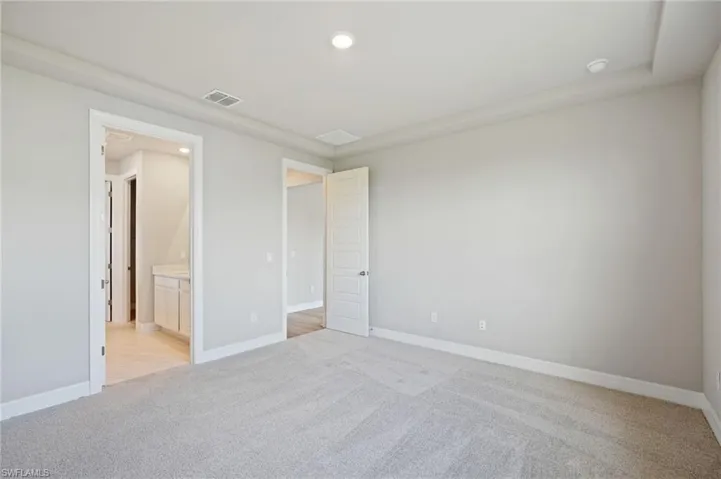 Unfurnished bedroom featuring light colored carpet and ensuite bathroom