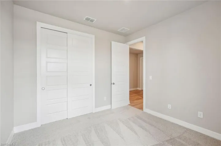 Unfurnished bedroom with light carpet and a closet