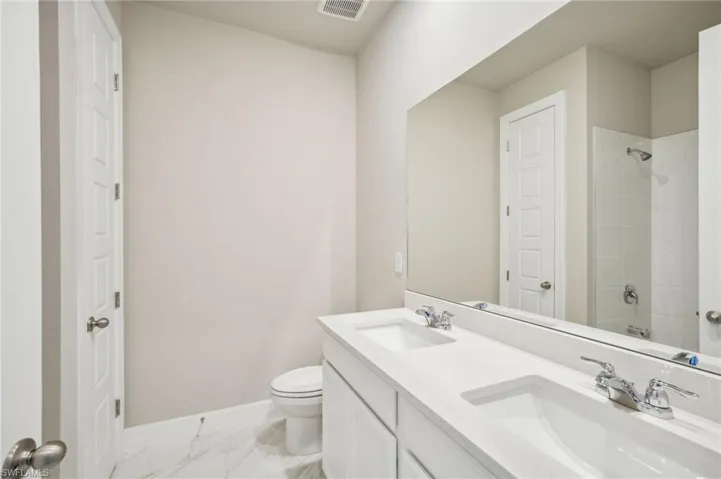 Bathroom featuring tiled shower, vanity, and toilet