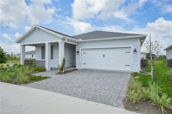 View of front of home featuring covered porch, central air condition unit, and a garage