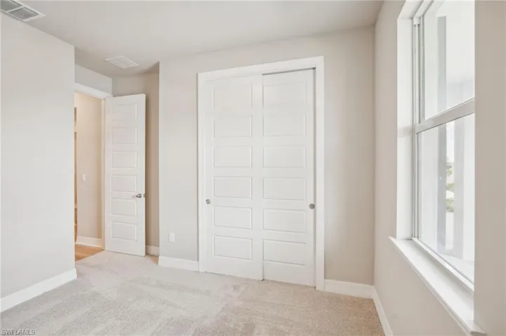 Unfurnished bedroom featuring light colored carpet and a closet