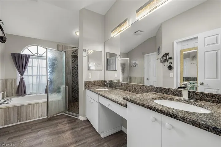 Bathroom with vanity, hardwood / wood-style flooring, independent shower and bath, and vaulted ceiling