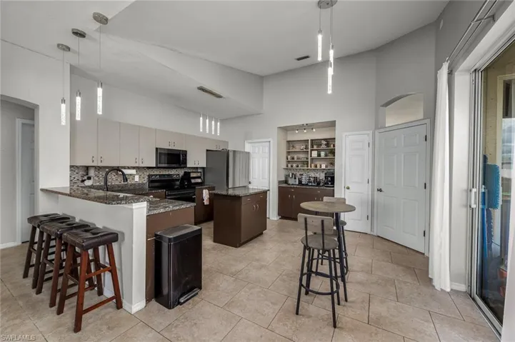 Kitchen with kitchen peninsula, tasteful backsplash, stainless steel appliances, and hanging light fixtures
