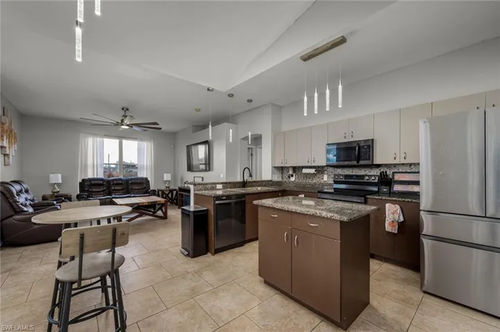Kitchen featuring sink, a center island, stainless steel appliances, vaulted ceiling, and pendant lighting