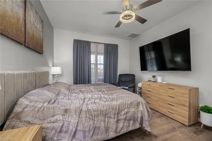Bedroom with ceiling fan, radiator heating unit, and hardwood / wood-style floors