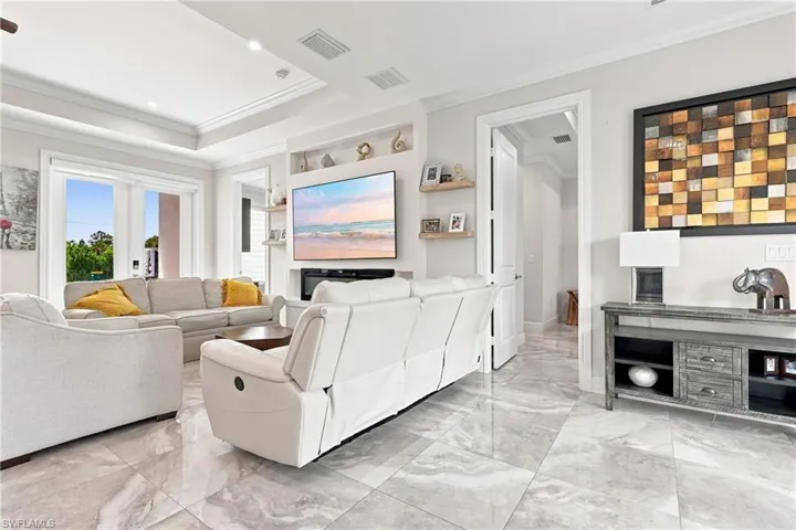 Recessed lighting, tray ceiling, built-in shelving, large format tile flooring, and French doors