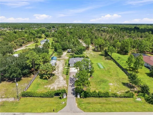 Expansive property featuring a paved driveway, lush green lawns, and mature trees