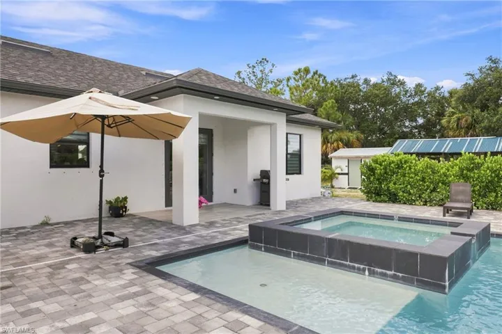 Spacious paver patio featuring a built-in pool and spa
