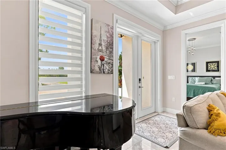 Tray ceiling with crown molding, double French entry doors, tile flooring, and a large window with horizontal blinds