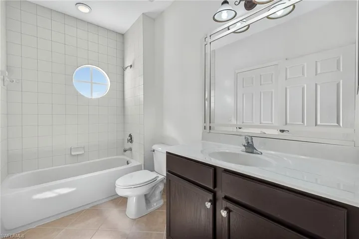 Bathroom with light tile patterned floors, tub / shower combination, and vanity